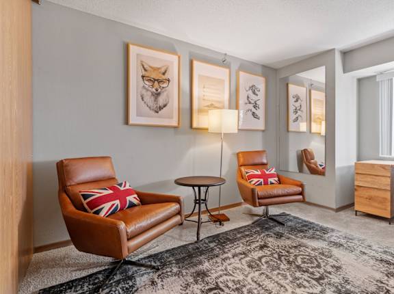 a living room with leather chairs and a rug and a window