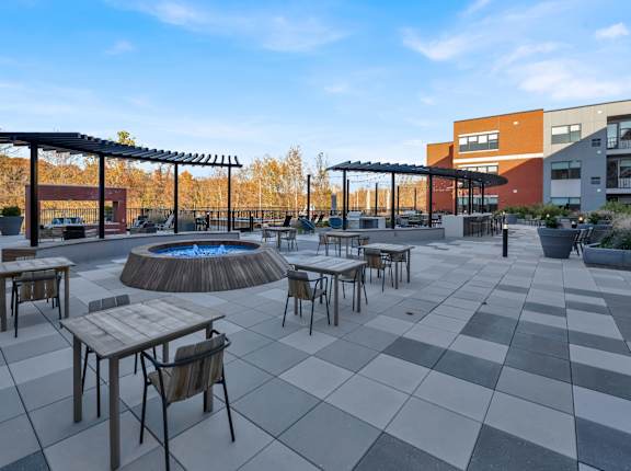 A patio with a fire pit and chairs.