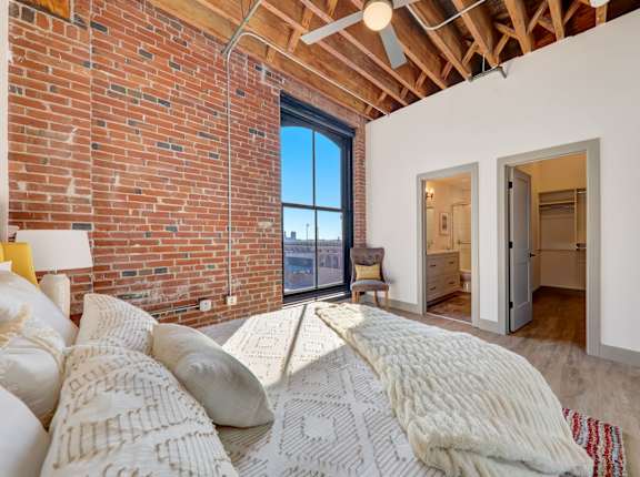 a bedroom with a bed and a brick wall at Greeley Lofts, St. Louis