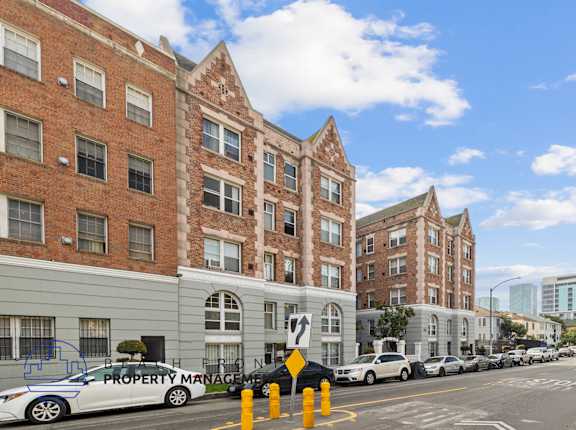 A street view of a row of buildings with cars parked on the side.