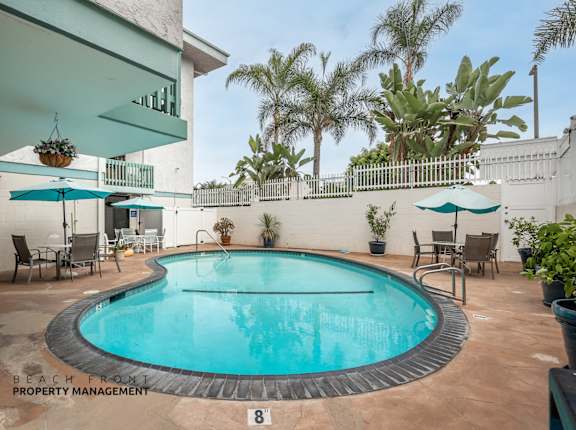 A pool surrounded by chairs and umbrellas with a sign that says "Beach from Property Management".