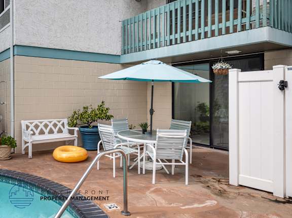 A poolside patio with a white table and chairs.