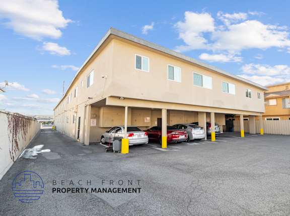 A parking lot with cars and a building with the sign "BEACH FRONT PROPERTY MANAGEMENT".