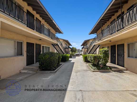 a long walkway between two buildings with balconies and bushes