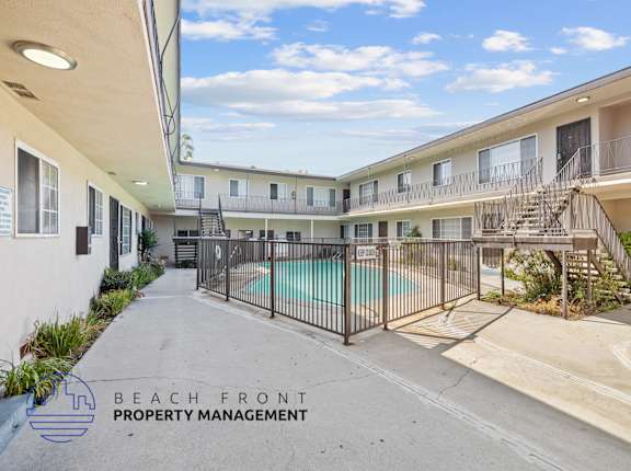 A pool area of a building with a sign that says "Beach Front Property Management".