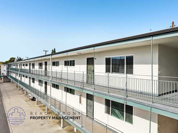 A row of white buildings with balconies and the logo of Beachfront Property Management in the bottom left corner.