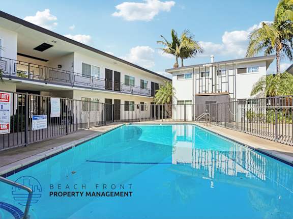 A swimming pool in front of a building with the words Beach Front Property Management.