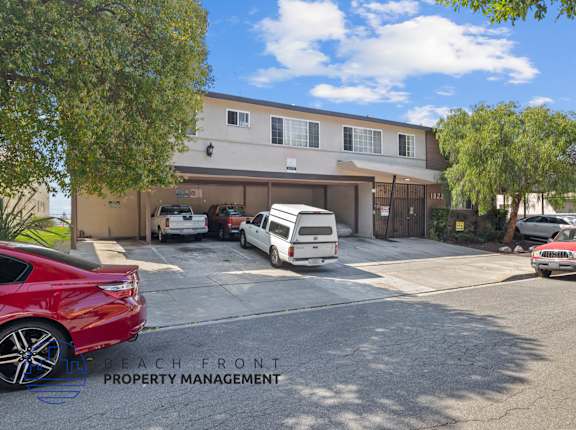 A red car is parked in front of a building with the sign "Beach Front Property Management".