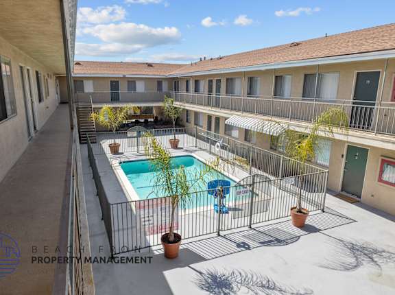 A pool surrounded by a fence and a building in the background.