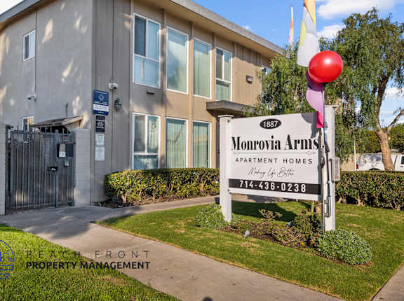 A sign for Monrovia Arms Apartment Homes is in front of a building.