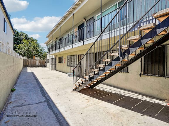 A long, narrow courtyard with a staircase leading to a building.