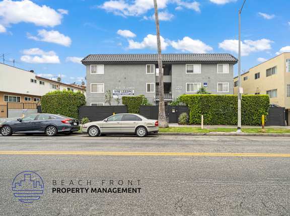 A street view with cars parked and a building with the sign "BEACH FRONT PROPERTY MANAGEMENT".