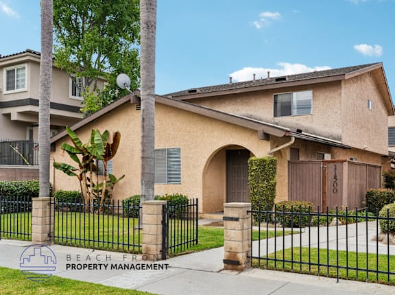 A house with a black fence and a sign that says "Beachfront Property Management".
