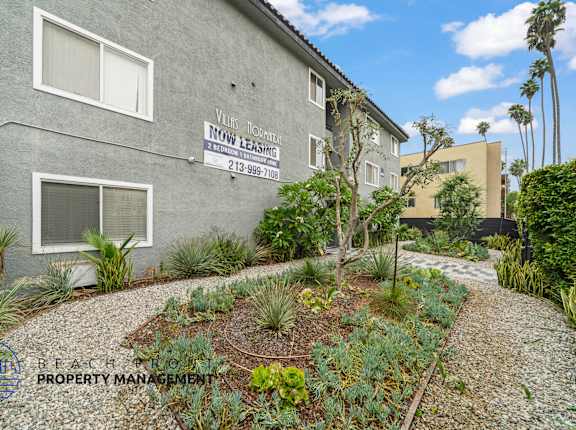 A grey building with a sign that says "Village Homeowners Association" and a phone number.