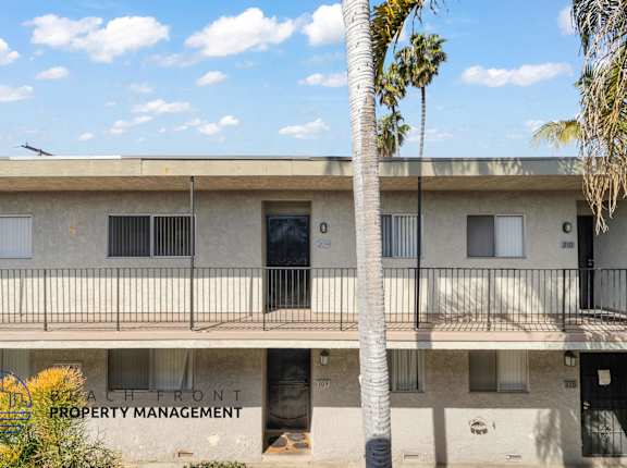 A building with a balcony and a palm tree in front of it.