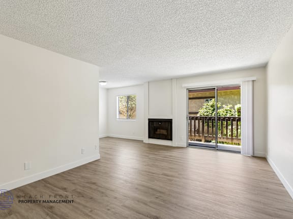 A spacious living room with a fireplace and sliding glass doors leading to a balcony.