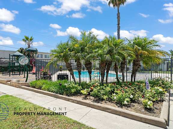 A pool area with a fence and a sign that says Beachfront Property Management.