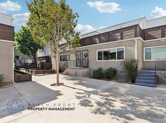 A courtyard with a tree and a building in the background.