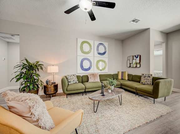 Spacious living room with couches, chairs, and a ceiling fan.
