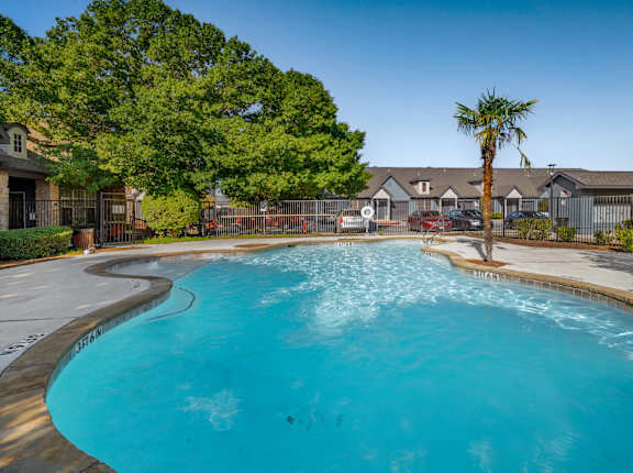 A large swimming pool surrounded by a fence and trees.