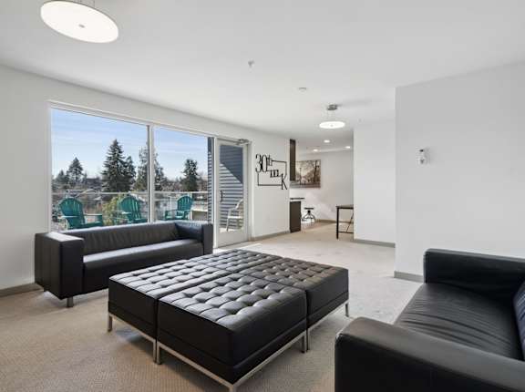 A black leather couch sits in a bright room with a large window.
