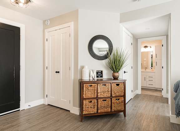 a living room with a dresser and a mirror on the wall