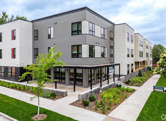 a view of a modern apartment building with a sidewalk