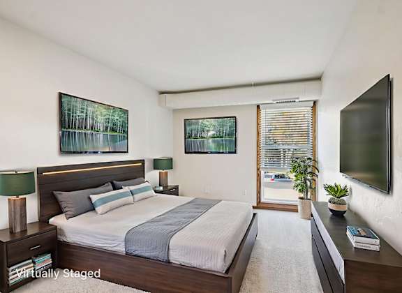 A bedroom with a large bed and a flat screen TV mounted on the wall.