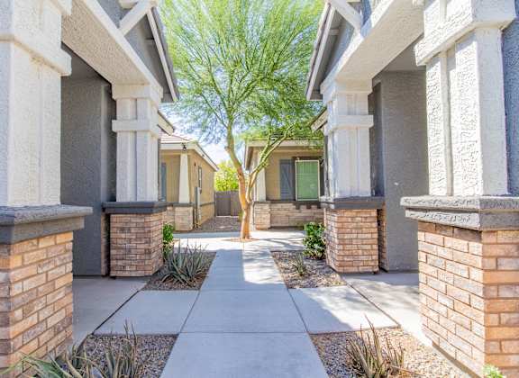 a walkway between two buildings with a tree in the middle at Villas on Olive in Peoria, AZ 85345