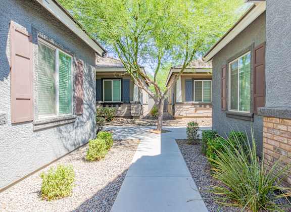 a walkway between two houses with trees and plants at Villas on Olive in Peoria, AZ 85345