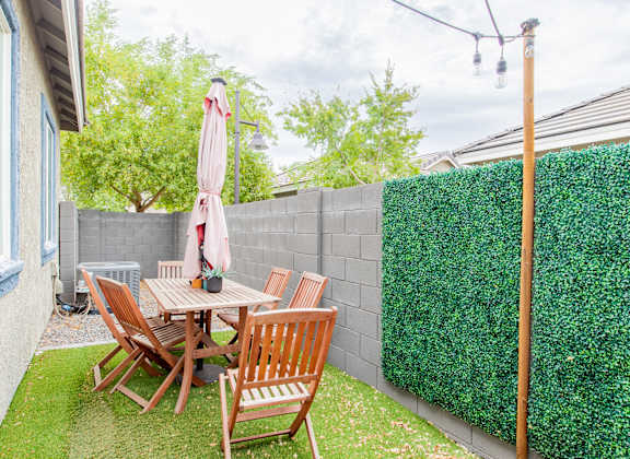 a backyard patio with a table and chairs and a privacy hedge at Villas on Olive in Peoria, AZ 85345