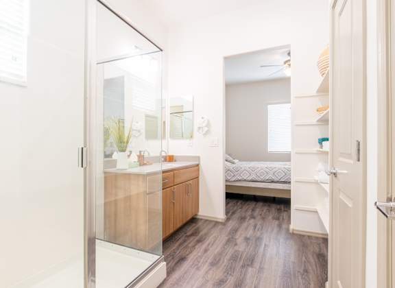 a bathroom with a shower and a sink and a bedroom at Villas on Olive in Peoria, AZ 85345