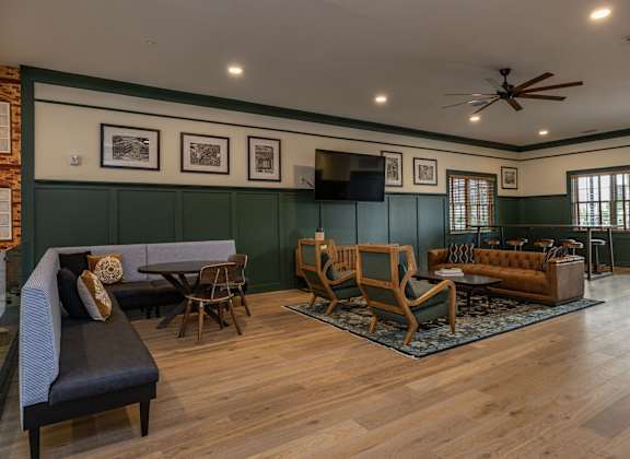 A living room with a grey sofa, wooden chairs, and a television.
