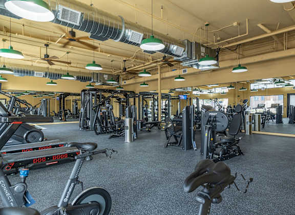 A gym with a variety of exercise equipment including treadmills, stationary bikes, and weight machines.