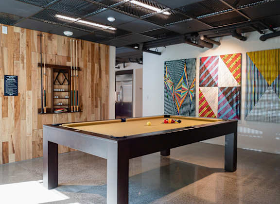 a billiards table in the lobby of a building with a wall of wood