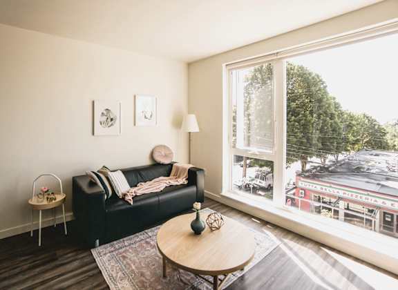 a living room with a large window and a black couch