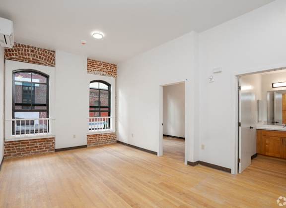 an empty living room with brick and white walls and wood floors