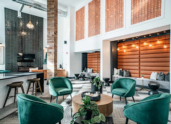 a living room with green chairs and a lobby with a fireplace
