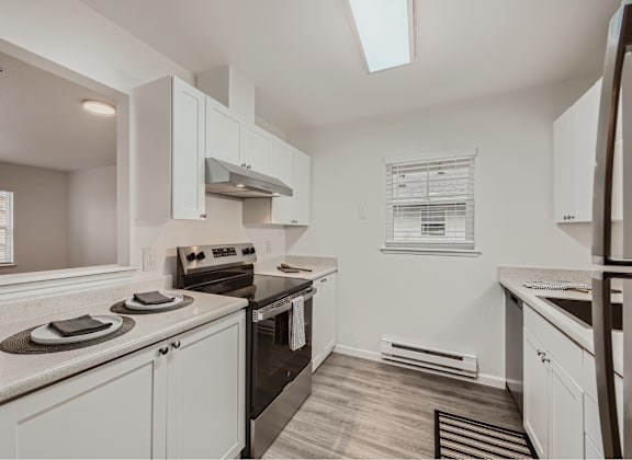 A kitchen with white cabinets and appliances.
