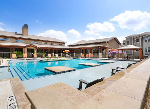 A large outdoor swimming pool with a diving board and a building in the background.
