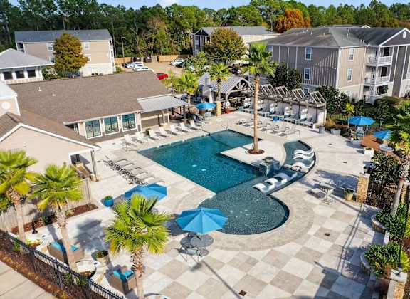 A large swimming pool surrounded by palm trees and lounge chairs.