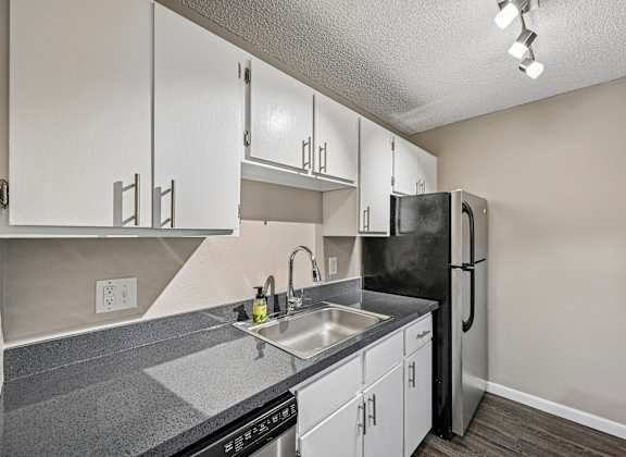 A kitchen with a black refrigerator and white cabinets.