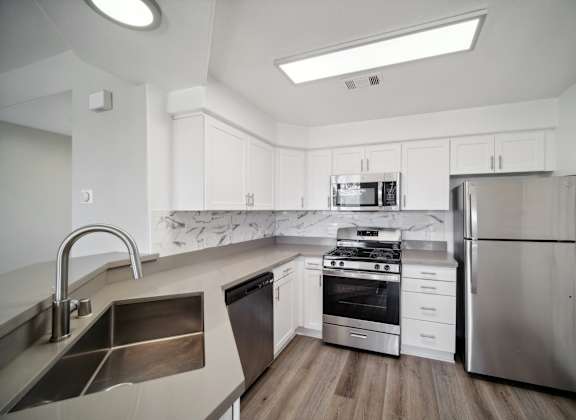 a kitchen with white cabinets and stainless steel appliances