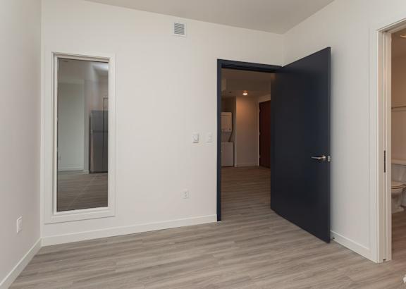 Empty bedroom with dark door and white framed mirror at Kaya Camilla, Portland