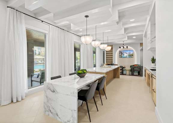 a long kitchen with a marble counter top and a long table with chairs