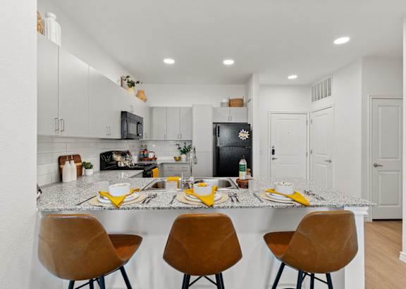a kitchen with a marble counter top and a bar with four chairs