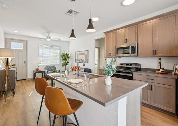 A modern kitchen with wooden cabinets and a central island at The Ranches at Gunsmoke, Maricopa, AZ