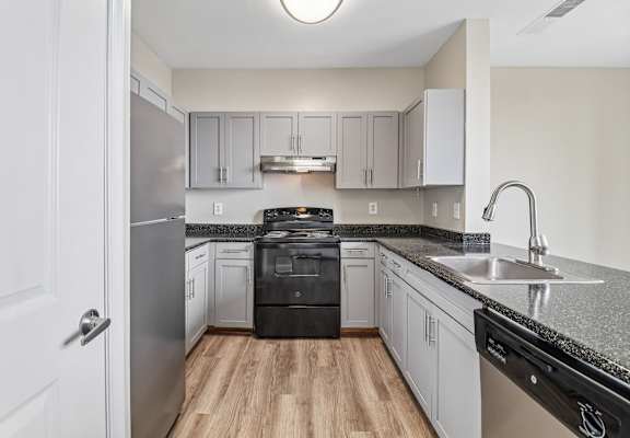 A kitchen with a black dishwasher and stove top oven.