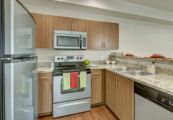 A kitchen with a stainless steel refrigerator, a microwave, a stove, and a dishwasher.