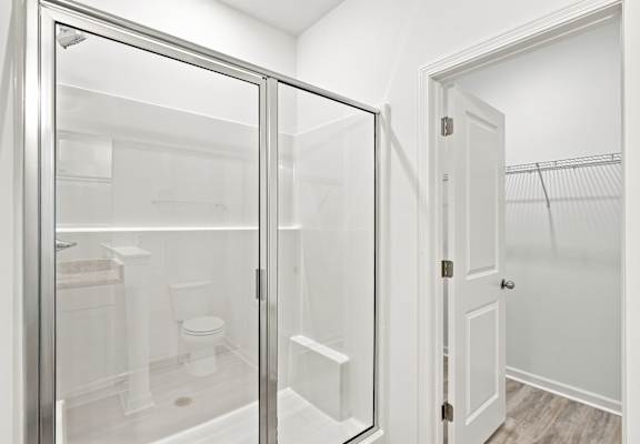 A white bathroom with a glass shower door.